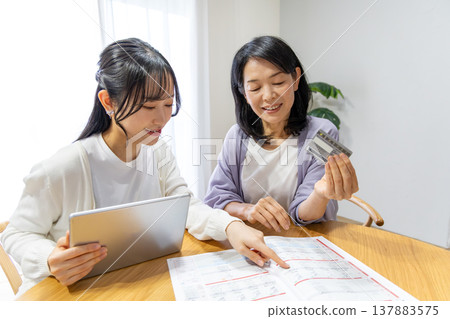 一對母女正在網路上瀏覽商品目錄。 137883575