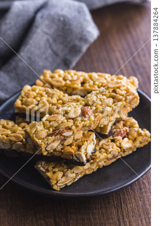 Stacked Peanut Bars With Chocolate Coating on Black Plate Rustic Snack Close-Up Stacked Peanut Bars With Chocolate Coating on Black Plate Rustic Snack Close-Up 137884264