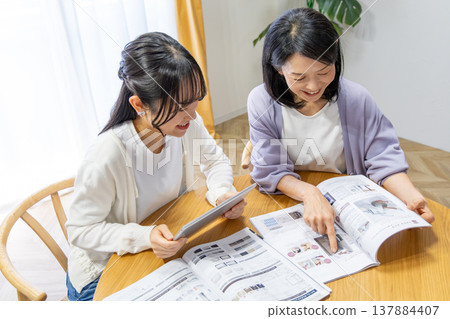 Mother and daughter looking at a catalog Mother and daughter looking at a catalog 137884407