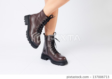 Women's brown spring boots made of genuine leather on a woman's leg. New collection of women's boots 2022 Women's brown spring boots made of genuine leather on a woman's leg. New collection of women's boots 2022 137886713