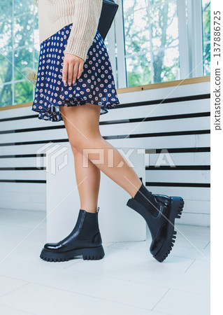 Close-up of black women's boots. Black boots made of genuine leather. Close-up photo of a woman's legs in warm boots Close-up of black women's boots. Black boots made of genuine leather. Close-up photo of a woman's legs in warm boots 137886725