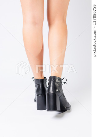 Fashionable woman in stylish leather shoes with heels. Female beautiful legs with fashionable boots in the studio on an isolated white background Fashionable woman in stylish leather shoes with heels. Female beautiful legs with fashionable boots in the studio on an isolated white background 137886759