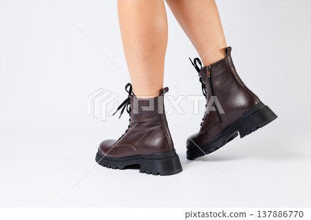Women's brown spring boots made of genuine leather on a woman's leg. New collection of women's boots 2022 Women's brown spring boots made of genuine leather on a woman's leg. New collection of women's boots 2022 137886770