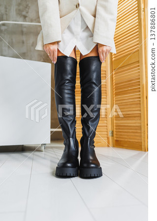 Beautiful female legs in black leather high boots. New collection of women's winter shoes. Boots-stockings Beautiful female legs in black leather high boots. New collection of women's winter shoes. Boots-stockings 137886801