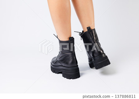 Woman in trendy black shoes on a white background, close-up. Woman's legs in stylish leather shoes 137886811