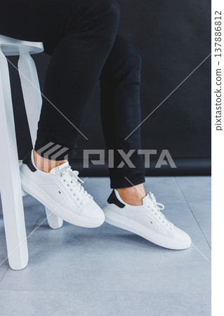 A man in white leather casual sneakers, summer men's sneakers. Man in black jeans 137886812