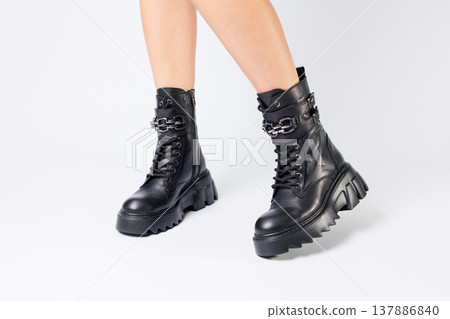 Legs of a woman in black leather boots from a new collection on a white background, legs of a girl in fashionable leather boots spring 2022. Legs of a woman in black leather boots from a new collection on a white background, legs of a girl in fashionable leather boots spring 2022. 137886840