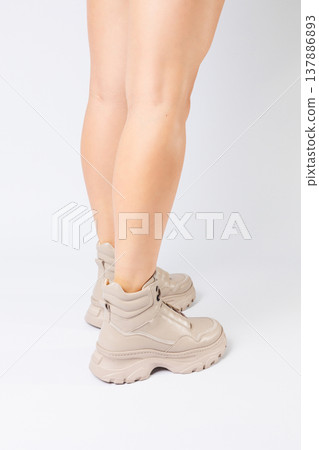 Female legs in beige leather shoes from the new collection on a white background female legs in fashionable shoes made of eco-leather spring 2022. Female legs in beige leather shoes from the new collection on a white background female legs in fashionable shoes made of eco-leather spring 2022. 137886893