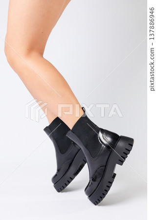 New collection of women's shoes spring 2022. girl's legs in new shoes. Legs in black boots. Low running boots made of genuine leather New collection of women's shoes spring 2022. girl's legs in new shoes. Legs in black boots. Low running boots made of genuine leather 137886946