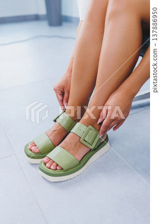 Female slender legs in green summer sandals. Women's leather shoes Female slender legs in green summer sandals. Women's leather shoes 137886950