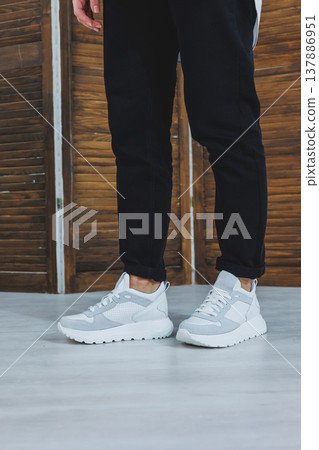 Beautiful women's shoes with legs, leather white sneakers, in the interior of a room or office, shoes for a woman, black trousers and white sneakers, casual and modern style, modern and trendy Beautiful women's shoes with legs, leather white sneakers, in the interior of a room or office, shoes for a woman, black trousers and white sneakers, casual and modern style, modern and trendy 137886951