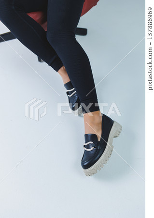 Female legs in black leather loafers. Autumn women's shoes without a heel 137886969