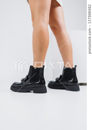 Women's legs in short chelsea boots with metal buckle, women's leather shoes. A fashionable collection of women's shoes 137886982