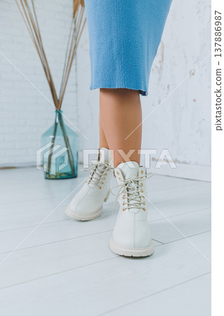 Close up of legs in stylish white shoes. Collection of women's shoes made of natural leather. Women's winter boots 137886987