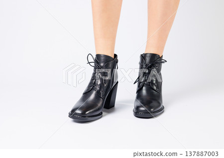 Fashionable woman in stylish leather shoes with heels. Female beautiful legs with fashionable boots in the studio on an isolated white background 137887003