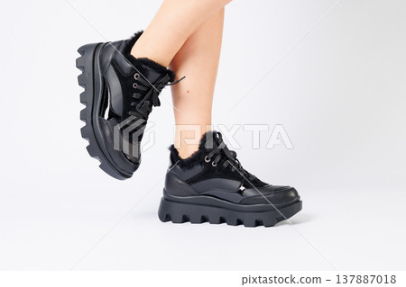 Fashionable black sneakers on the legs of a woman in the studio on a white background. Legs of a young girl with beautiful trendy shoes 137887018