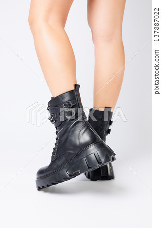 Legs of a woman in black leather boots from a new collection on a white background, legs of a girl in fashionable leather boots spring 2022. Legs of a woman in black leather boots from a new collection on a white background, legs of a girl in fashionable leather boots spring 2022. 137887022