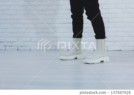 Women's legs close-up in white autumn boots. Women's boots made of genuine leather 137887026