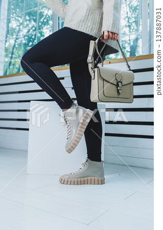 Close up of legs in stylish white shoes. Collection of women's shoes made of natural leather. Women's winter boots Close up of legs in stylish white shoes. Collection of women's shoes made of natural leather. Women's winter boots 137887031