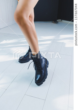 Close-up of black women's boots. Black boots made of genuine leather. Close-up photo of a woman's legs in warm boots 137887044