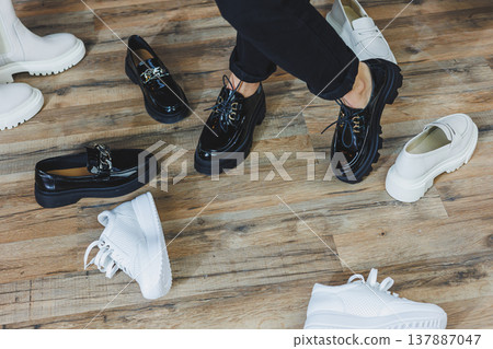 A woman chooses shoes against a brick wall. Several pairs of women's leather shoes A woman chooses shoes against a brick wall. Several pairs of women's leather shoes 137887047