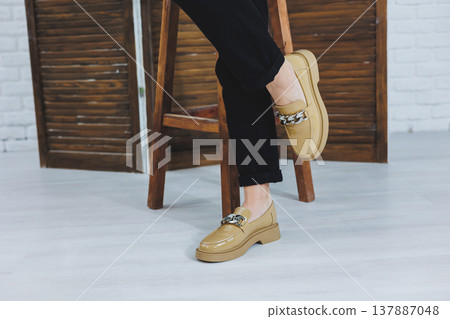 Close-up of female legs in black jeans in stylish leather beige shoes. Fashionable woman in new loafers. Modern seasonal collection of stylish shoes. Women's fashion. Close-up of female legs in black jeans in stylish leather beige shoes. Fashionable woman in new loafers. Modern seasonal collection of stylish shoes. Women's fashion. 137887048