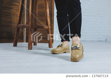 Close-up of female legs in black jeans in stylish leather beige shoes. Fashionable woman in new loafers. Modern seasonal collection of stylish shoes. Women's fashion. 137887114