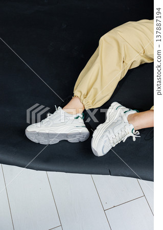 Casual women's fashion. Comfortable shoes for women. Female legs in pants and white stylish casual sneakers. Women's comfortable summer shoes. 137887194