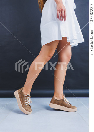 Women's brown leather sneakers on the legs close-up. Collection of summer women's shoes Women's brown leather sneakers on the legs close-up. Collection of summer women's shoes 137887220