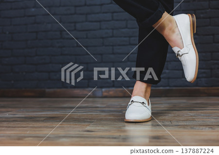 Close-up female legs in black trousers and leather beige moccasins. New spring-summer collection of women's leather shoes 2022 Close-up female legs in black trousers and leather beige moccasins. New spring-summer collection of women's leather shoes 2022 137887224