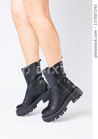Women's black spring boots made of genuine leather are dressed on bare feet Women's black spring boots made of genuine leather are dressed on bare feet 137887243
