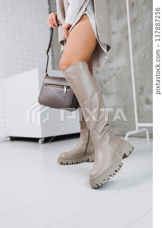 Close-up of female legs in beige leather boots. Women's winter shoes. Warm women's boots 137887256