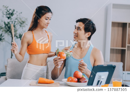 A happy couple prepares fresh vegetables, laughing and enjoying cooking a healthy meal together. A happy couple prepares fresh vegetables, laughing and enjoying cooking a healthy meal together. 137887305