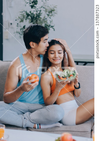 A happy couple prepares fresh vegetables, laughing and enjoying cooking a healthy meal together. 137887323