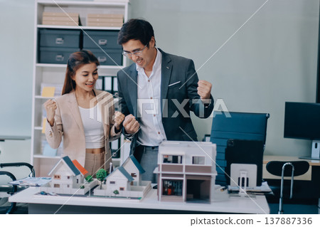 Real Estate Broker discussing with a customer model install solar roof house modern project in the office, real estate developer alternative energy, development business sustainable, zero energy, ESG. 137887336