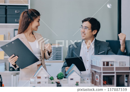 Real Estate Broker discussing with a customer model install solar roof house modern project in the office, real estate developer alternative energy, development business sustainable, zero energy, ESG. 137887339