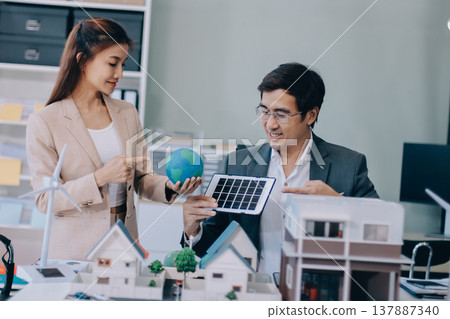 Real Estate Broker discussing with a customer model install solar roof house modern project in the office, real estate developer alternative energy, development business sustainable, zero energy, ESG. 137887340
