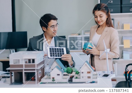 Real Estate Broker discussing with a customer model install solar roof house modern project in the office, real estate developer alternative energy, development business sustainable, zero energy, ESG. 137887341