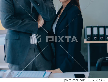 Portrait of a happy Asian business couple standing together. Young professional man and woman smiling in studio. Corporate teamwork concept 137887382