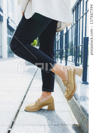 Female legs in black jeans and beige high heels. Beige leather shoes close-up 137887394