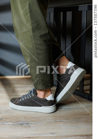 Male legs in gray casual sneakers. Comfortable men's summer shoes. 137887396