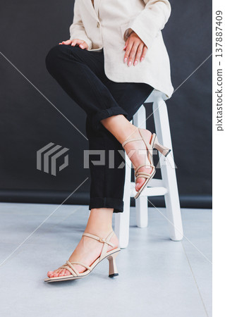 Women's legs close-up in summer brown flip-flops with heels. Summer collection of shoes for women made of genuine leather Women's legs close-up in summer brown flip-flops with heels. Summer collection of shoes for women made of genuine leather 137887409