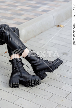 Slender female legs close-up in genuine leather boots. New collection of women's spring shoes Slender female legs close-up in genuine leather boots. New collection of women's spring shoes 137887435