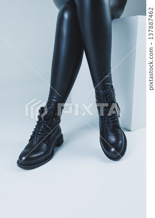 Female legs in leather black autumn boots. A fashion girl stands in a store and measures shoes. 137887462