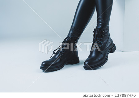 Female legs in leather black autumn boots. A fashion girl stands in a store and measures shoes. Female legs in leather black autumn boots. A fashion girl stands in a store and measures shoes. 137887470