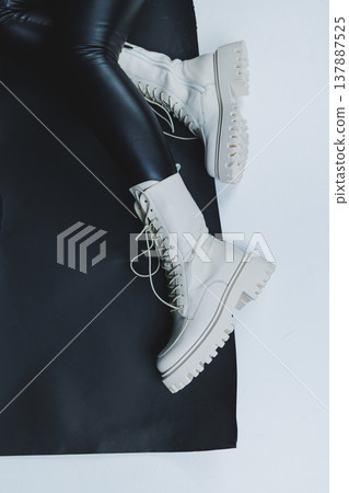 Close up of female legs in stylish fashion leather white lace up shoes. New seasonal collection of women's winter shoes. Close up of female legs in stylish fashion leather white lace up shoes. New seasonal collection of women's winter shoes. 137887525