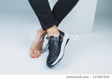 Men's feet, one in sneakers and one barefoot. Men's casual shoes. Men's feet, one in sneakers and one barefoot. Men's casual shoes. 137887639