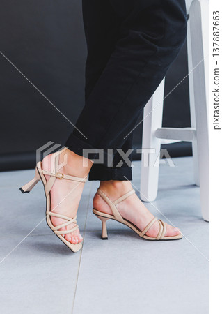Women's legs close-up in summer brown flip-flops with heels. Summer collection of shoes for women made of genuine leather 137887663