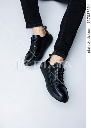 Close up of male legs in black jeans and black leather casual sneakers. Comfortable men's demi-season shoes Close up of male legs in black jeans and black leather casual sneakers. Comfortable men's demi-season shoes 137887664