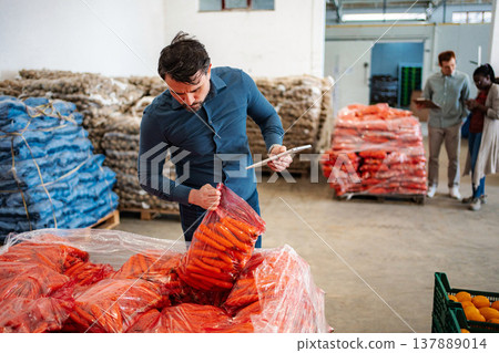 Man checking carrots quality in food warehouse Man checking carrots quality in food warehouse 137889014